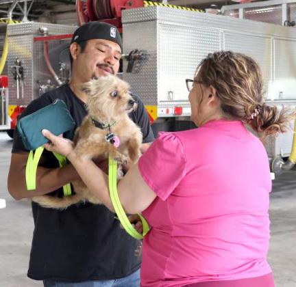 As Ricardo Rios of the Lamb County Veterinary Hospital takes this pup, it seems to say” MOM! DID YOU SAY “SHOTS!!” at the Rabies Clinic held at the Littlefield Fire Department on Saturday, May 11, 2024. (Photo by Ann Reagan)