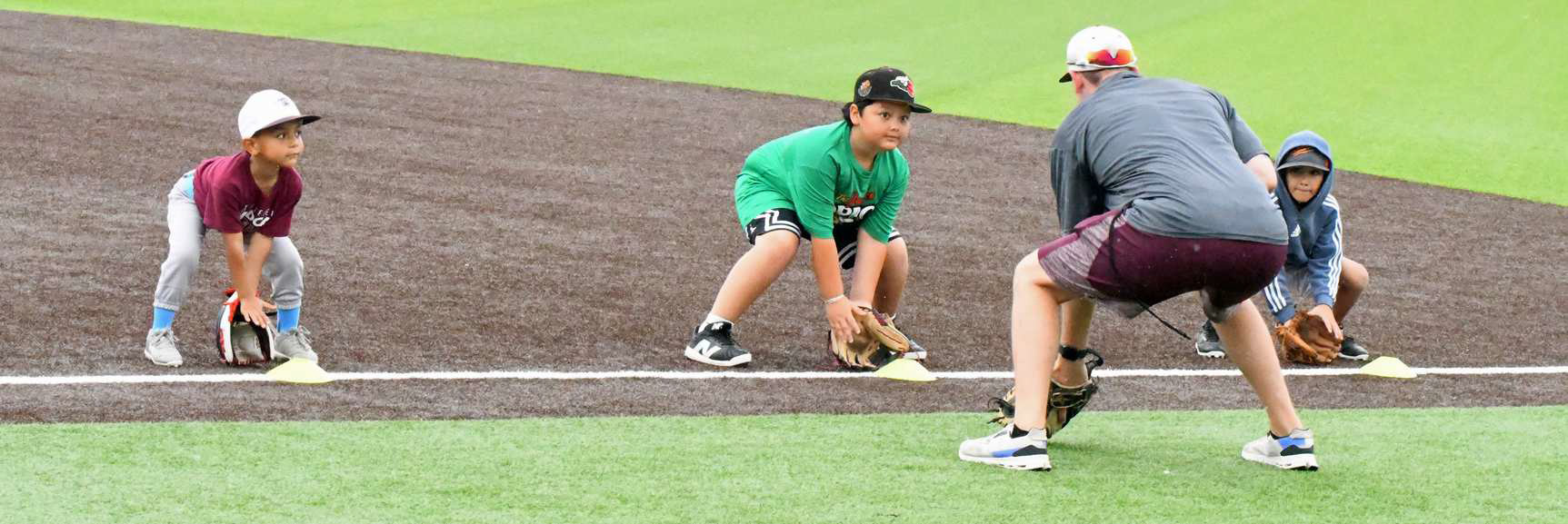 Littlefield Head Baseball Coach, Jett Hartley, works with a group of kids on good fielding position, during the morning session of the 2025 youth baseball camp at Wildcat Field Tuesday morning. (Staff Photo by Derek Lopez)