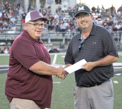 WAR ON 84 - Littlefield Booster Club President Brad Heffington and Muleshoe President Todd Shipman shake hands as the check is presented for the proceeds from the War on 84 T-Shirt sales. The check was presented during halftime of the annual War on 84 football game that took place on August 25th in Muleshoe this year, with the Mules coming out victorius, 48-20. The T-Shirt sales raised a total of $5,000 which was split evenly between two families that wished to remain anonymous. (Photo by Gabby Perez)