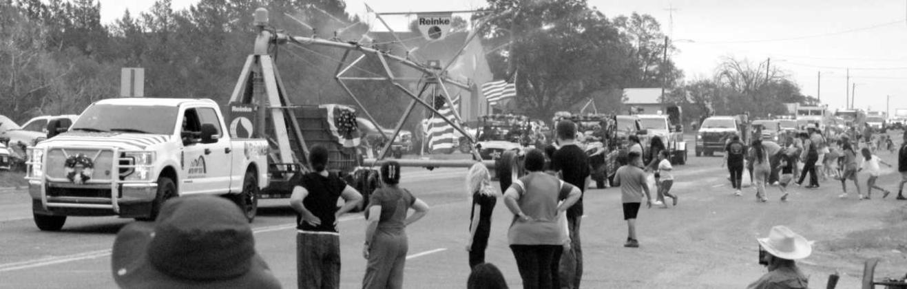 United Pivot Techs pull a pivot down the highway, spraying spectators with water during the Springlake Fourth of July parade.