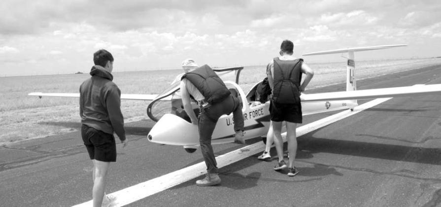 Air Force cadets are preparing a TG15A glider for takeoff and assisting pilots as they board the glider on the runway during training operations. (Photo by Leon Szaniszlo)