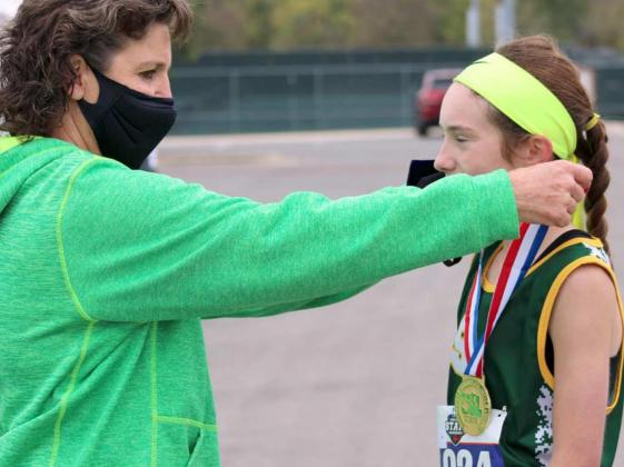 SHARING THE MOMENT — Springlake-Earth Head Girl’s Cross Country Coach Jeri Been Goodman got to share a special moment with her daughter, Taytum Goodman, at the 1A State Cross Country Meet at Old Settler’s Park in Round Rock last month. Shown is Coach Goodman, draping her daughter with her gold medal, after Goodman won the 1A Girl’s State Cross Country Meet with a time of 11:18.29, setting a 1A Girl’s State record. (Submitted Photo)