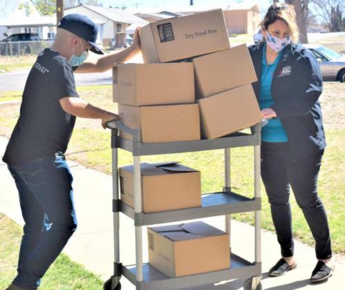 MOVING FOOD TO COMMUNITY CENTER – Adrian Reyes and Patricia Consalez transfer food boxes from delivery bus to the Community Center, where they will be picked up for the recipients. (Photo by Ann Reagan)