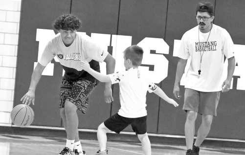 Olton varsity basketball player, Alex Green, dribbles through a drill for a camper to work on their defense, during camp on Monday, May 25th. (Staff Photo by Derek Lopez)