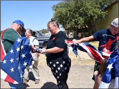 Members of the Guardians of Old Glory carefully prepare a US Flag for its retirement at the Lamb County Ag Center on Saturday, September 9,2023. The organization replaces worn out flags with flags in good condition and new flags as they are available for free. Flag retirements are usually held once every 3 months whenever possible. (Photo by Ann Reagan)