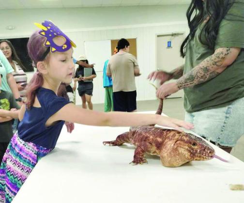 Attending families pet a Red Tegu during the Lamb County Library’s Summer Reading Program finale on July 1. (Photo by Leon Szaniszlo)