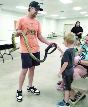 Attendees pet a Tiger Rat Snake during a live animal exhibit at the Lamb County Library’s Summer Reading Program closing party on July 1. (Photo by Leon Szaniszlo)