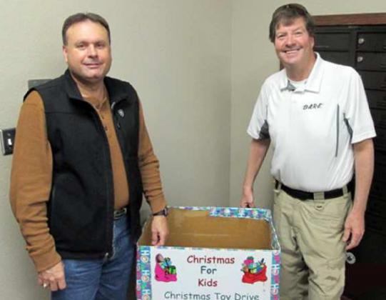 TOY COLLECTION BOXAT SHERIFF’S OFFICE—Lamb County Sheriff Gary Maddox, left, and DARE Deputy Michael Armstrong, are shown with the toy collection box that is placed in the foyer of the Sheriff’s office. The 20th “Christmas for Kids” toy drive is now underway, and is receiving applications for children who need help with Christmas gifts. Pick up an application at the Sheriff’s Office, or at any of the banks at the various cities in the county. (Photo submitted by Sheriff’s Office)