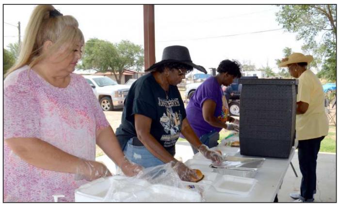 MAKING FOOD TRAYS of hamburgers, chips and pound cake for shut-ins and pickup at Dunbar Park during the annual Juneteenth Celebration. (Staff Photo by Samantha Pontius)