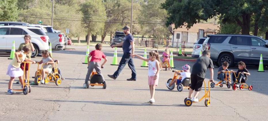 Primary children enjoy riding in safety on the Littlefield Primary Parking lot as parents and teachers visit in the shade at the Primary Back to School Picnic held on Monday, August 26, 2024