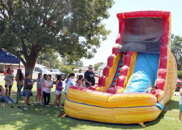 Children line up to cool off on the water slide at the Jamaica Day hosted by the Sacred Heart Catholic Church on Sunday, August 25, 2024. (Photo by Ann Reagan)