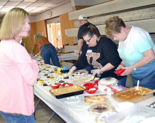 WORKING WITH DESSERTS – Placing desserts on serving dishes for Bob Edwards’ 13th annual Fish Fry, in honor of his 88th birthday, were, left to right, Gina Hayes, Sheri Tooley, and Jamie Seymour. (Staff Photo by Joella Lovvorn)