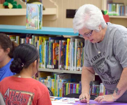 Sussan Bell gives instructions and assists kids in painting during the Lamb County libraries’ Painting workshop on July 16. (Photo by Leon Szaniszlo)
