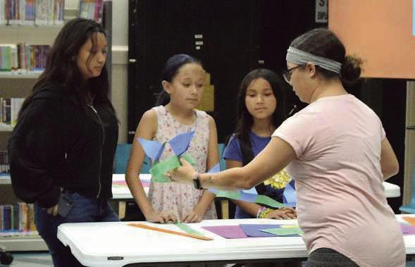 Assistant Librarian Ambrosia Simpson gives instructions on how to create paper dinosaur tails during the Lamb County Library’s T-Rex Tea Party on June 18.