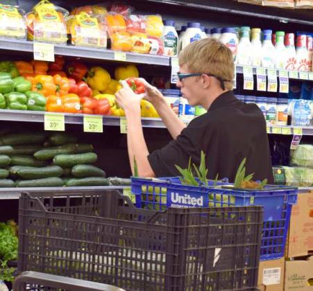 AIDAN SCAFF carefully inspects and stocks fresh produce at the United Supermarket of Littlefield. (Photo by Ann Reagan)