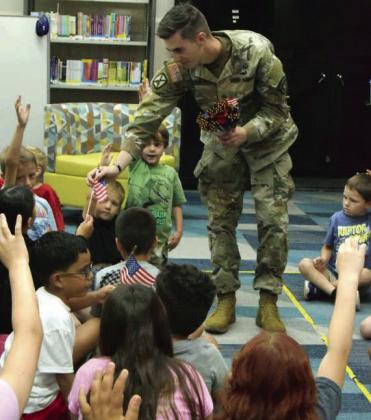 SSG Eric Comes with the United States Army, hands out flags while kids say what they are thankful for during the Lamb County library’s summer reading program on June 24. (Photo by Leon Szaniszlo)