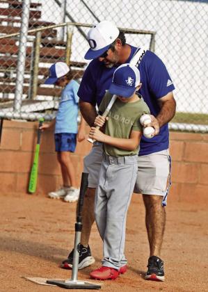 Olton Head Baseball Coach, Kris Cavazos, helps a camper get set in the box, during the morning session of baseball camp last Thursday in Olton. (Staff Photo by Derek Lopez)