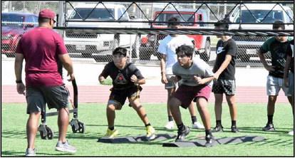Littlefield Coach Jose Delacruz and Matthew Arce work with a group of campers at the chutes, as they work on staying low out of their down stance, during day one of the Wildcat Youth Football Camp on Monday. (Staff Photo by Derek Lopez)