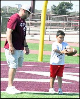 Littleifled Head Coach Bo Bryant, helps a young camper learn to punt, during day one of the Wildcat Youth Football Camp on Monday at Wildcat Stadium in Littlefield. (Staff Photo by Derek Lopez)