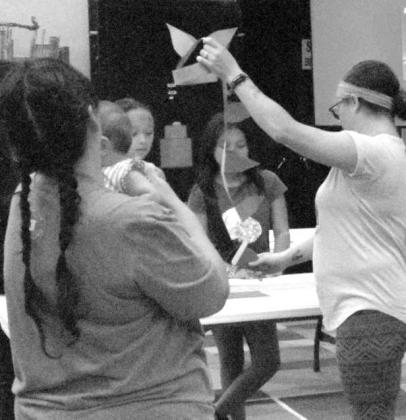 Assistant Librarian Ambrosia Simpson shows kids a completed paper dinosaur tail while explaining the arts and crafts activity to children at the Lamb County Library’s T-Rex Tea Party on June 18.