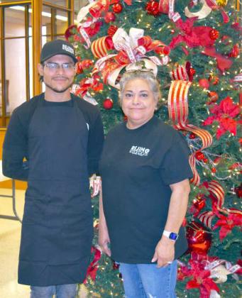 Left to Right- Justin Ramon and Willlma Everett served delicious BBQ with all the trimmings at the Open House hosted by Wellington State Bank of Littlefield on Tuesday, Dec. 6th. Mia Gonzalez, manager of Rejino BBQ of Olton arranged the catering. (Photo by Ann Reagan)