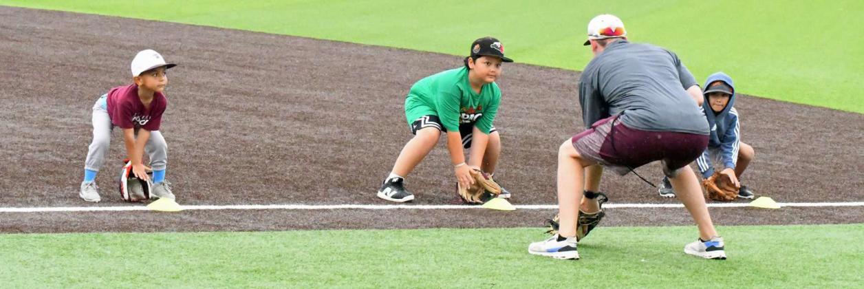 Littlefield Head Baseball Coach, Jett Hartley, works with a group of kids on good fielding position, during the morning session of the 2025 youth baseball camp at Wildcat Field Tuesday morning. (Staff Photo by Derek Lopez)