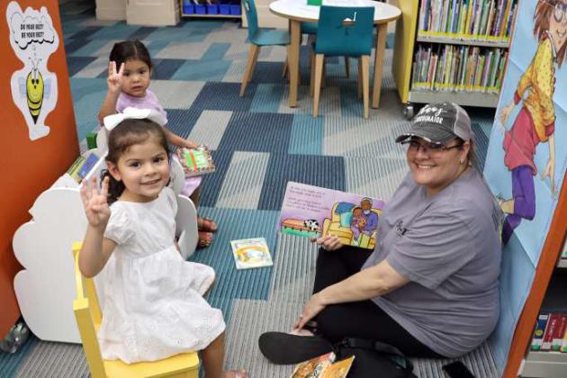 Aracely Saldana age 3 and Olivia Leal, age 3, were enjoying a book read to them by Birdy Coronado. (Photo by Ann Reagan)