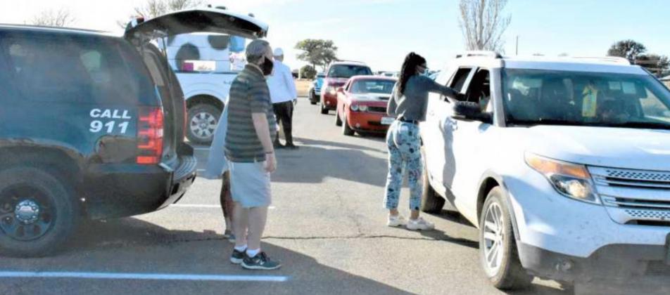 DELIVERING SACKS OF GOODIES—Volunteers were working Saturday evening for Lamb Healthcare Center’s Halloween Drive-thru Trunk or Treat event, as the cars stopped and the children rolled the windows down to receive their sacked treats. The vehicle on the left is one from the Littlefield Police Department, and we suppose the volunteers are from that department. (Photo by Krista Carpenter)