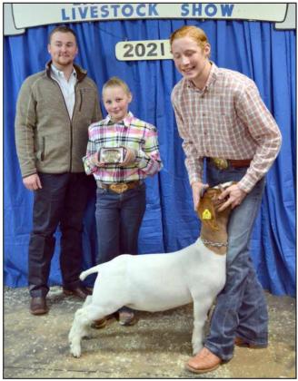 GRAND CHAMPION GOAT— Samuel Hill of Littlefield’s Division II goat took the Grand Champion Goat honors Saturday, Jan. 9, 2021, during the Lamb County Junior Livestock Show. He is shown with the show judge, Kinder Harlow, on the left, and someone special holding his belt buckle award, in center. (Staff Photo by Joella Loworn)