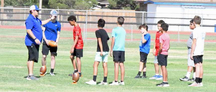 Olton Coach James Dougherty explains to a group of campers how to kick off of a tee, during the first day of the Olton Youth Football Camp on Monday. (Staff Photo by Derek Lopez)