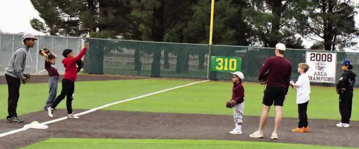 CJ Weaver and Chip Green work with a group of campers during the first day of the Wildcat Youth Baseball Camp last Wednesday. (Staff Photo by Derek Lopez)