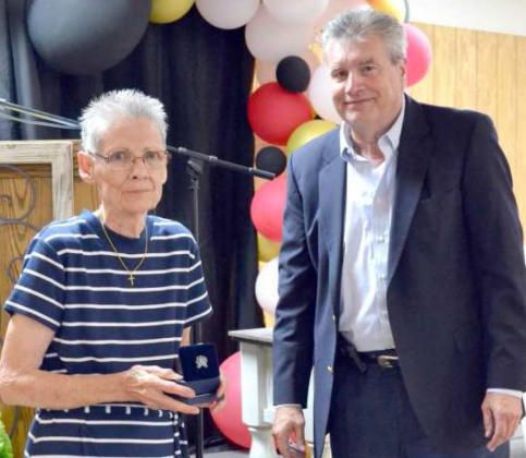 JEAN STREETY accepted the “Woman of the Year” Award on behalf of her daughter, Gina Streety, who was a victin of the COVID-19 virus. with her is John Roley, who gave her a silver coin.
