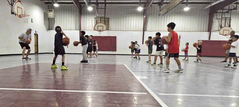 Littelfield varsity basketball coach, Nathan McKinnon, demonstrates getting into triple threat position, during the first day of basketball camp on Monday, June 8th. (Staff Photo by Derek Lopez)