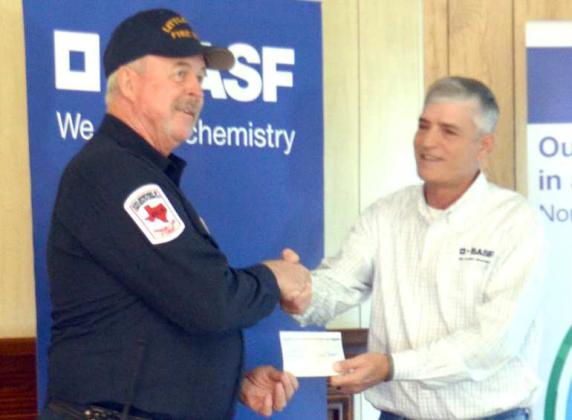 During a presentation on Tuesday at BASF in Littlefield, Tony Scolley is shown presenting Littlefield Fire Chief Jaime Grey with a donation to go towards a new fire engine. (Staff Photo by Samantha Pontius)