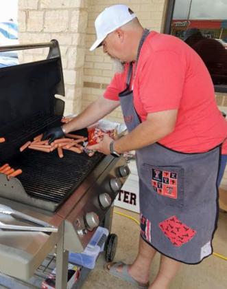 First Federal Bank’s Jason Hunter cooks hot dogs for their annual 3rd of July event, that took place last Thursday in the bank parking lot. (Staff Photo by Derek Lopez)