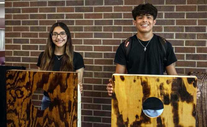 Meah Gonzales and Ben Castillo pose alongside the cornhole boards they constructed throughout the semester on May 2, 2025. (Staff Photo by Madison Vidales)
