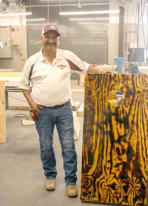 Littlefield woodworking teacher, Ray Vargas, proudly stands with one of the Cornhole Boards that was constructed by his students over the course of this semester. (Staff Photo by Madison Vidales)