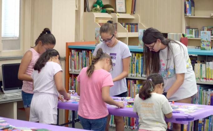 Julie-Ann Bownds helps kids make custom bookmarks at the Lamb County Library’s craft night on July 9. (Photos by Leon Szaniszlo)