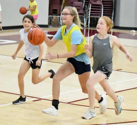 BRINGING THE BALL UP – A Littlefield summer camper fends off the defense as she brings the ball down court, during a pick-up game at the afternoon session of the Littlefield Girl’s Summer Basketball Camp on Tuesday at Wildcat Gym. (Staff Photo by Derek Lopez)