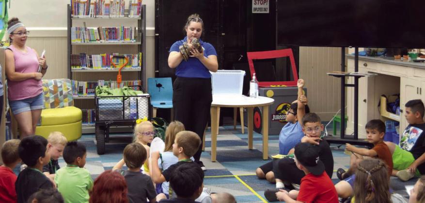 Above and below: During an educational presentation at the Lamb County Library on Wednesday, June 10, STEM educator Mac Richard from the Lubbock Science Spectrum holds a boa constrictor as children sit on the floor and watch. (Photos by Leon Szaniszlo)