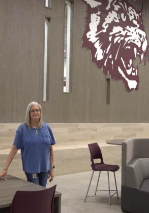 Ann Ray stands inside Littlefield High School in front of the Wildcats mascot, reflecting on her decades-long career serving the district. (Photo by Leon Szaniszlo)