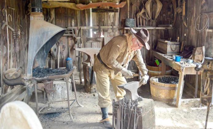 RANCH HOST Lewis Neely fires up the forge in the blacksmith shop in preparation for Ranch Day. (Photo by John Weast)