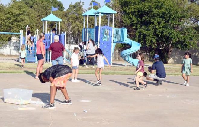 GUESTS OF LITTLEFIELD PRIMARY enjoy Sidewalk Art on the basketball court and the activities offered on the playground structure during the Third Annual Back to School cookout on Monday, August 21, 2023. (Photo by Ann Reagan)