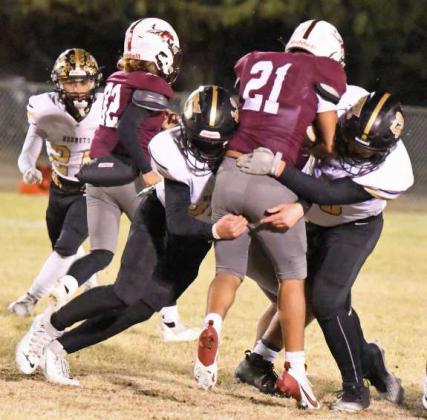 Andrew Larson (62) and Westen Cannon (59) combine to take down Ralls’ Evan Ybarra on a rush attempt up the middle, during their district match-up Friday night. (Staff Photo by Derek Lopez)