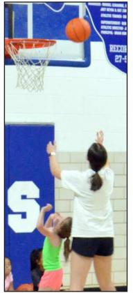 Volunteer, Aspen Struve, helping a girl from session two catch the ball during a game.