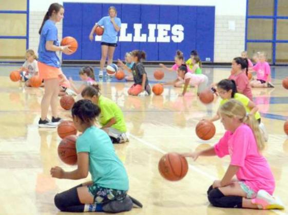 Coach Huseman showed the girls of session two how to bounce the ball by slappng it with their hands. Assistant Kayla Mandrell (left) and volunteer Mac Smith (top middle) were helping the girls.