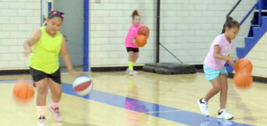 Coach “T” Tomison taught the girls of session two how to work on better hand-eye coordination by having them dribble two balls at once while walking up and down the court. (Photo by Samantha Pontius)