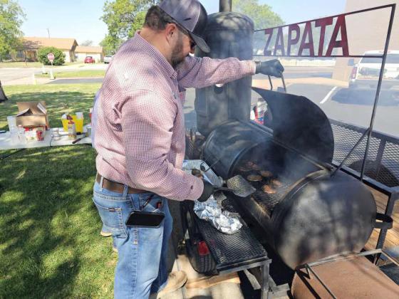 Steven McCain and Oscar Zapata prepare burgers and hot dogs for a retirement luncheon for Hilda Miranda, Peggy Robison and Tami McGehee. (Staff Photo by Derek Lopez)