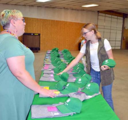 PLACING 4-H YEAR AWARDS–Kathy Lostroh, leader volunteer, and 4-H member, Bonnie Reese, were working out the placements of the 4-H T-Shirts and green 4-H caps in the order of the number of years the 4-H’ers have been 4-H members. (Staff Photo by Joella Lovvorn)