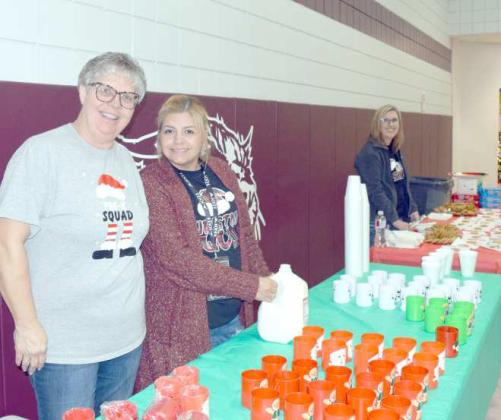 Pam Foshee and Suzanne Cruz served Chocolate Chip cookies and milk at the Primary Family Christmas Party. (Photo by Ann Reagan)